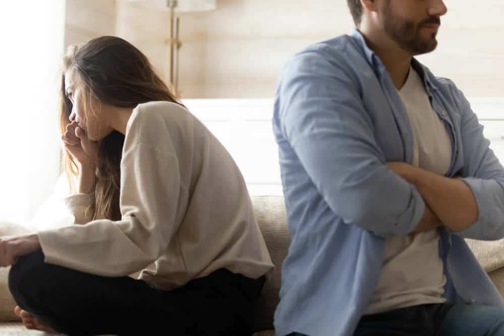 A couple sits back to back, upset with one another.